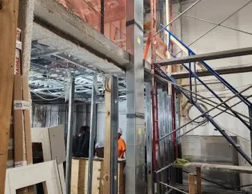 A construction worker is standing in the middle of a building.