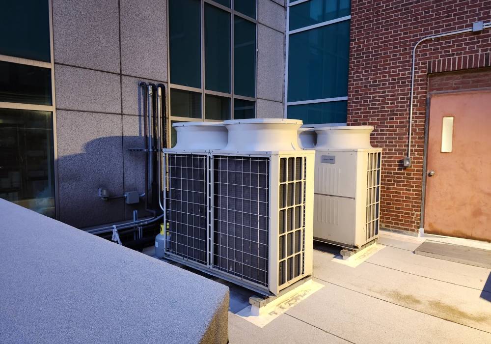 Two air conditioners are on the side of a building.